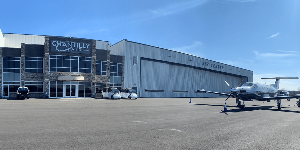 Outside view of Chantilly Air Jet Center with hangar doors closed and private plane on runway