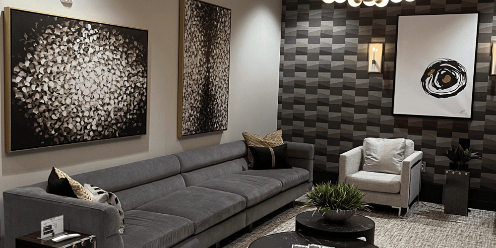 The inside of Chantilly Air's FBO designed with modern paintings, a grey sofa and white arm chair surrounding a black coffee table.