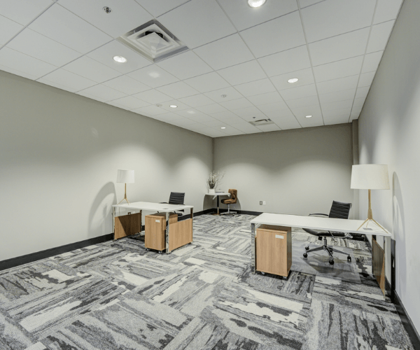 Modern first-floor office space with furnished desks, seating, and neutral finishes located near an FBO lobby