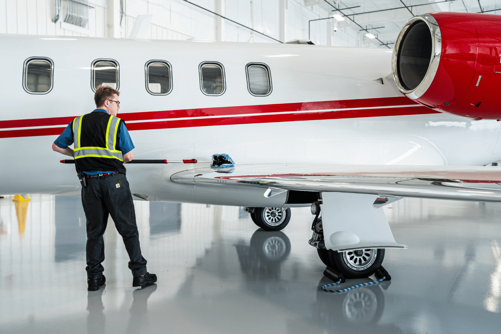 Chantilly Air line service technician providing aircraft wing cleaning and ground handling support inside the hangar.