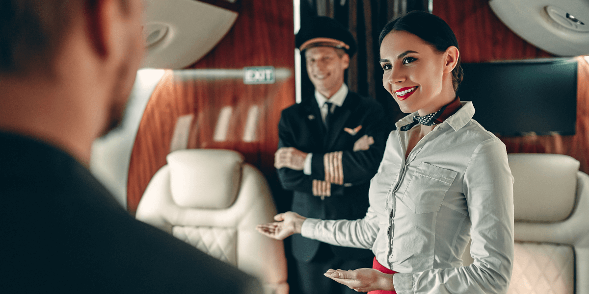 Flight attendant and pilot showing guest to their seat on a jet.