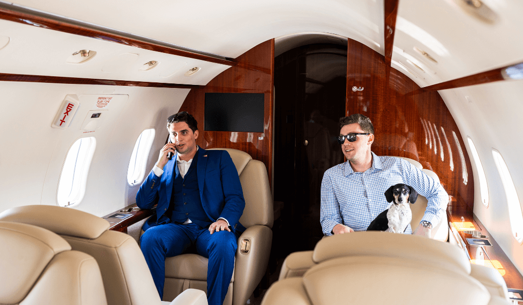 Two men and a dog sitting in a private jet.