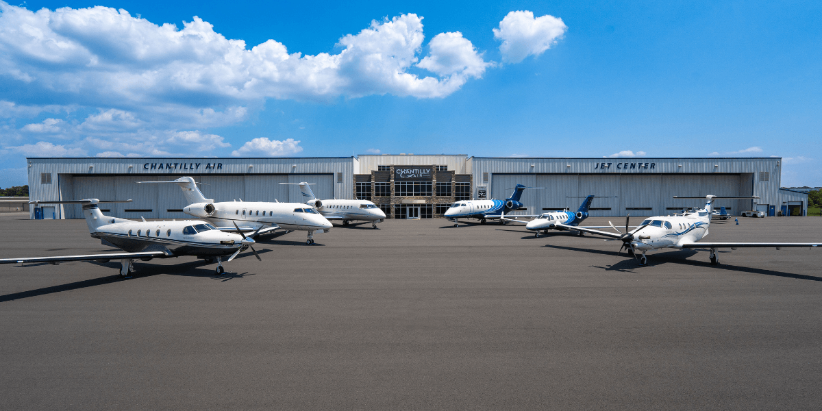 Two rows of aircraft lined up parallel to each other in front of Chantilly Air hangar.