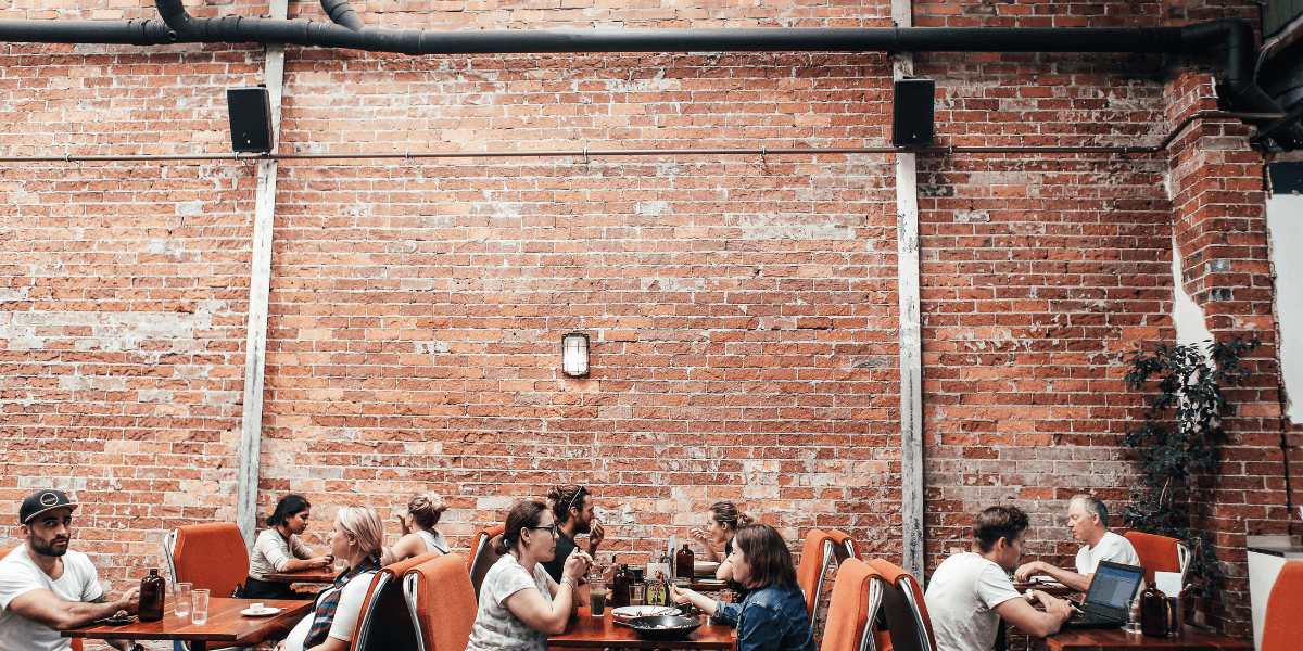 Exposed brick wall with tables set up full of customers eating.