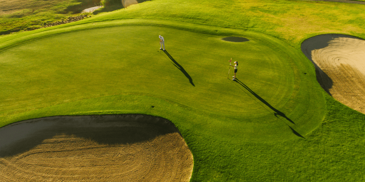 Golf course with two players putting.