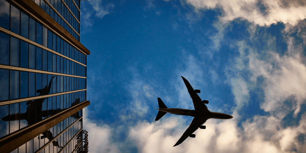 Airplane flying by a skyscraper.