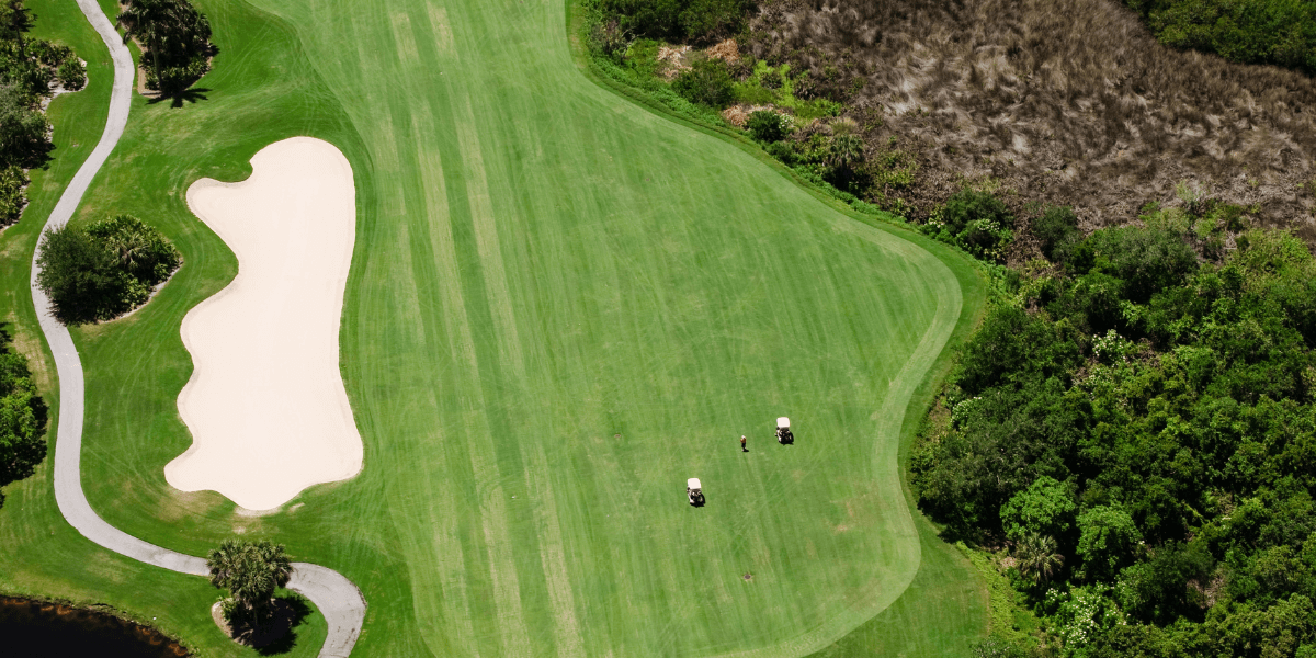 High overview of a golf course with two golf carts in view.