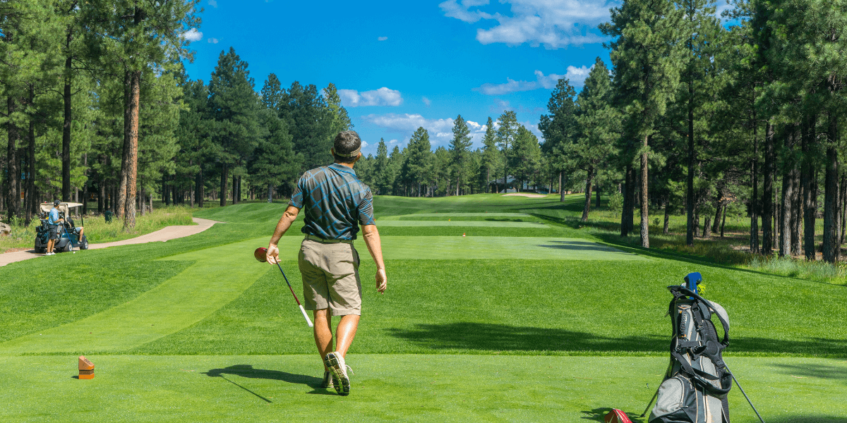 A man on a golf course after just swinging.
